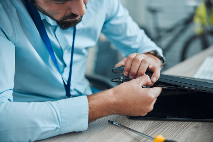 A computer service technician program grad is troubleshooting a laptop in a training lab